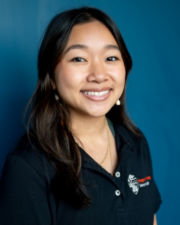 Jazlyne smiling for portrait in front of blue background