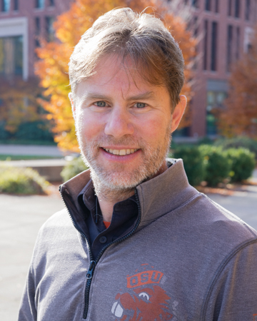 Adam smiling for a headshot in front of the Learning Innovation Center