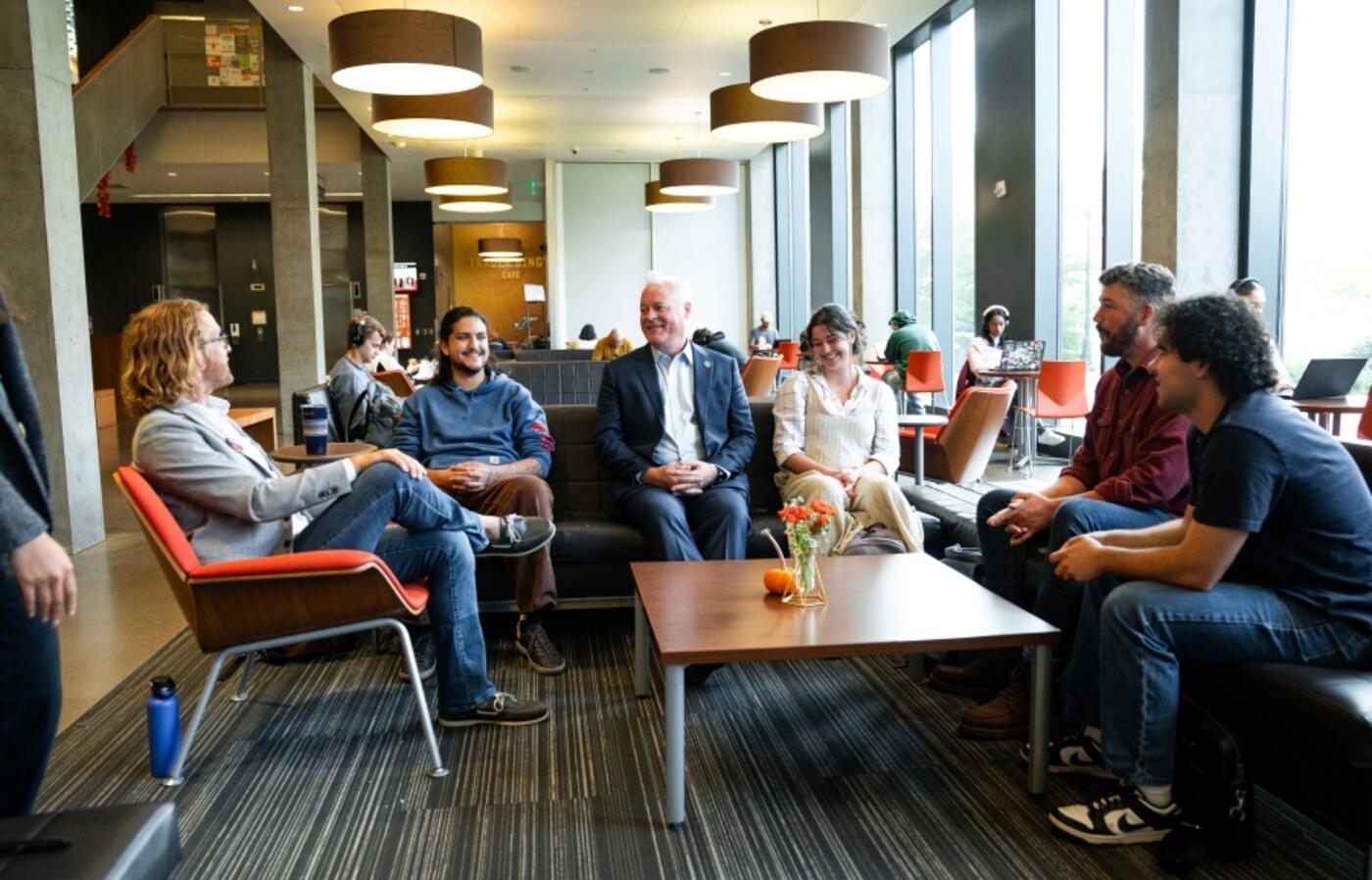 Dean of the COB Tim Caroll and students, alumni, and instructors involved in the OSU College of Business Discourse Program sit around a table in Austin Hall.