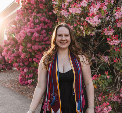 Grace Knutson smiling in front of a pink flower bush in her HC stole