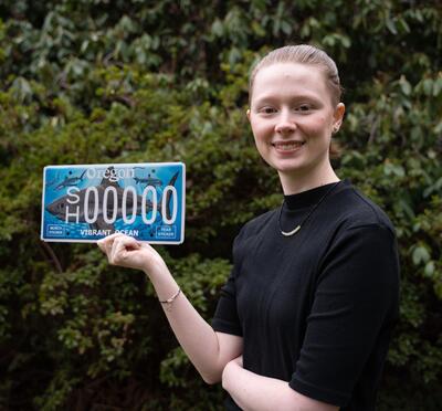 Natalie smiling with her license plate in her hands