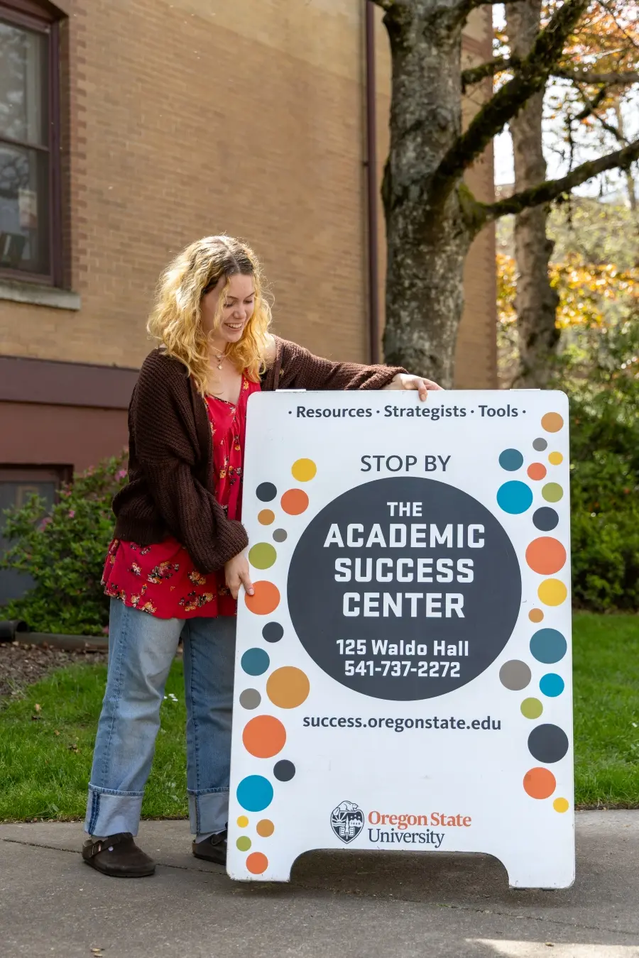 Student placing an Academic Success Center sign on the ground.
