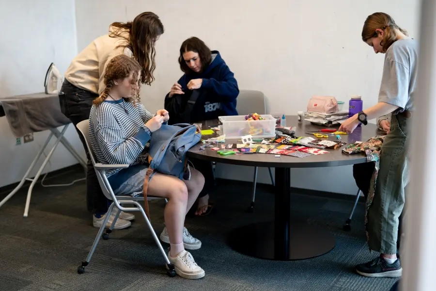 Seminar students help repair backpacks and clothing items in the SLUG.