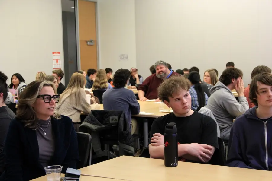 Students sit around tables in a classroom during the “Scholars or Suckers: Is Higher Education a Swindle?” discourse event.
