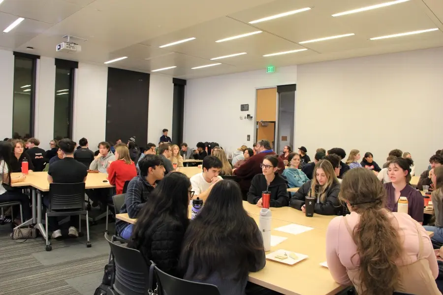 Students sit around tables in a classroom during the “Scholars or Suckers: Is Higher Education a Swindle?” discourse event.