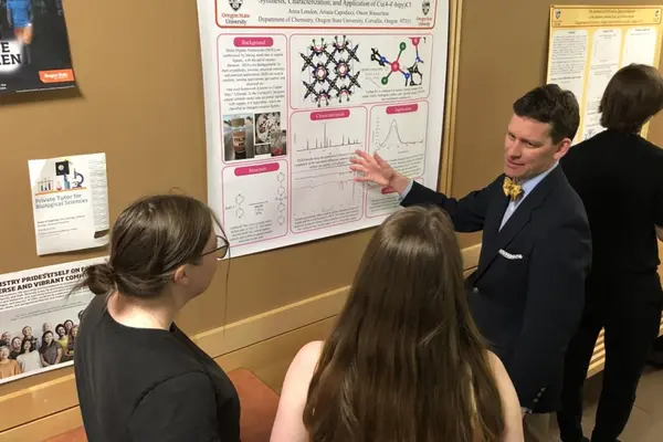 three students discussing a chemistry poster