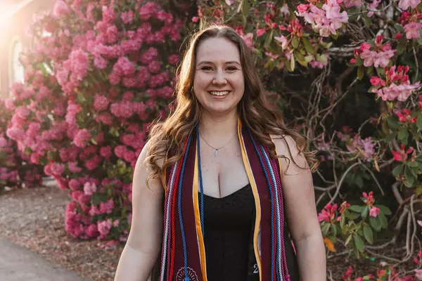 Grace Knutson smiling in front of a pink flower bush in her HC stole