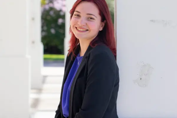 Alex Saccente leaning against a white building 