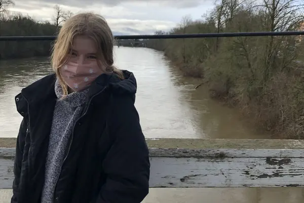 Grace Petrina standing on a bridge overlooking a river