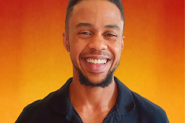 Levi Daniels smiling brightly for a portrait in front of an orange gradient background