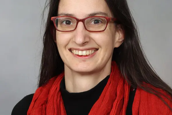 Marguerite Robinson smiling for a portrait in a red glasses and red scarf