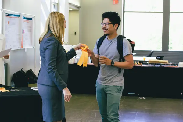 A poster winner being handed their ribbon