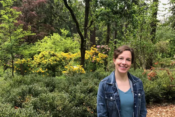 Eliza smiling in front of green trees