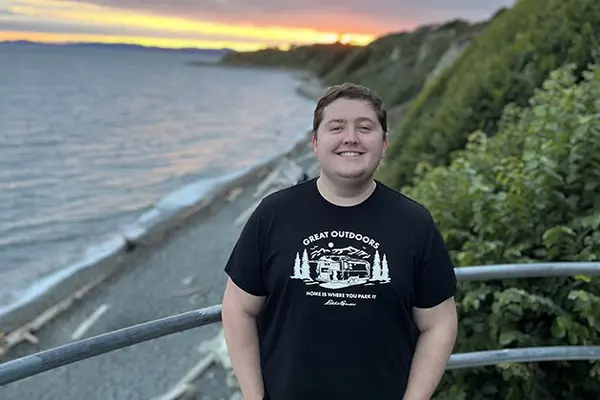 Josh stands in front of a sunset on the beach 