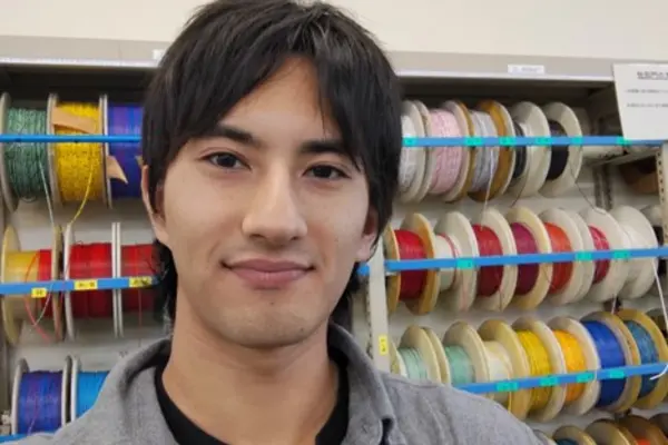 Shion standing in front of a wall of wires at a truck technology testing facility