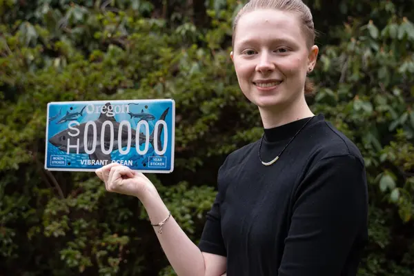Natalie smiling with her license plate in her hands