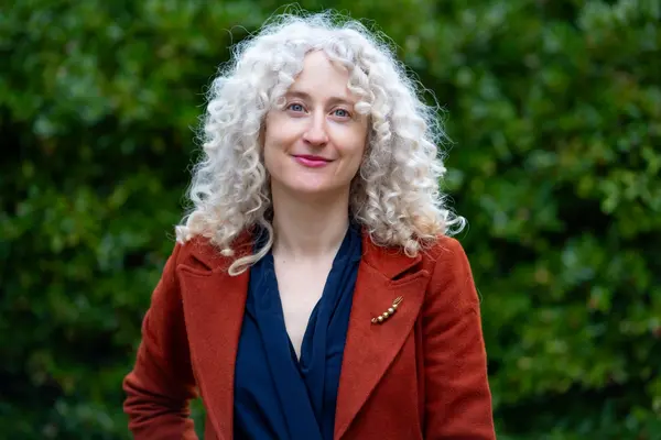 Katherine smiling for a portrait in front of greenery
