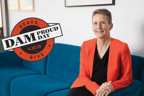 Dean Doolen smiling on couch with Dam Proud Day Logo laid on image