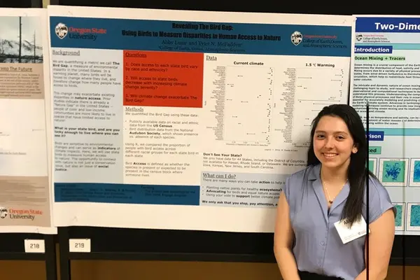 Abby Luna smiling with thesis project poster