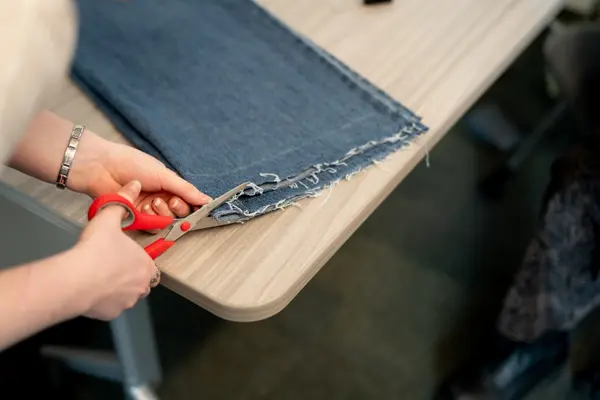 A seminar student cuts a piece of denim during the Thrift and Repair fair.