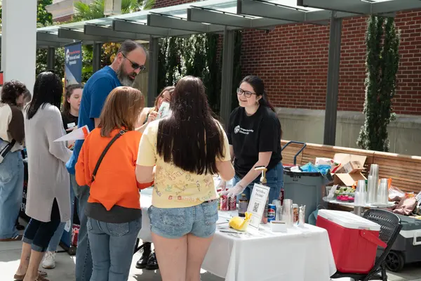 Honors student engages community members at the Honors College table during the Dam Proud Day Street Fair, where honors students sold dirty sodas to raise funds for HC student scholarships.